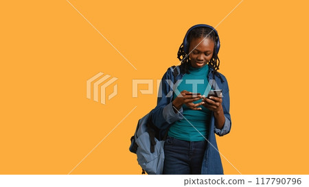 African american teenager adding payment method on website, isolated over studio background. Young girl wearing headphones, doing internet shopping, typing credit card information on phone, camera B African american teenager adding payment method on website, isolated over studio background. Young girl wearing headphones, doing internet shopping, typing credit card information on phone, camera B 117790796