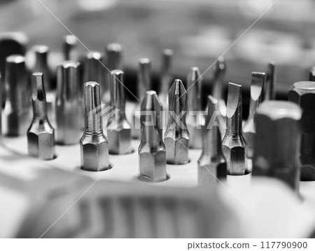 Various small screwdriver bits in different shapes and sizes, captured in a selectively focused image, black and white color Various small screwdriver bits in different shapes and sizes, captured in a selectively focused image, black and white color 117790900