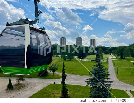 Cable car in the city park with green grass and blue sky. Aerial view Cable car in the city park with green grass and blue sky. Aerial view 117790903