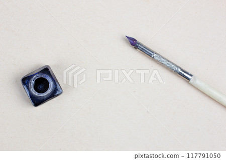 Vintage pen and inkwell on paper background Vintage pen and inkwell on paper background 117791050