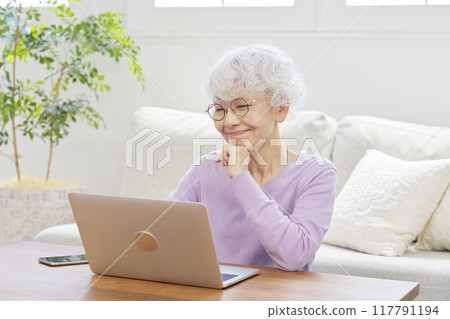 Senior woman using laptop in living room 117791194