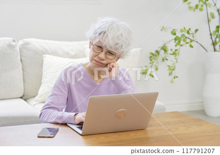Senior woman worried while using a laptop computer in living room Senior woman worried while using a laptop computer in living room 117791207