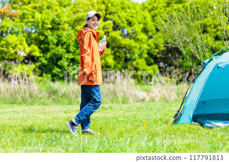 Young woman hydrating at a campsite 117791813