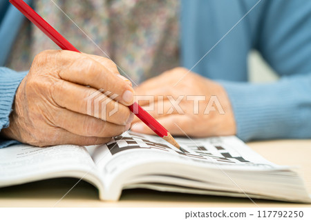 Alzheimer disease AD, Asian elderly woman playing sudoku puzzle game to practice for dementia prevention. 117792250