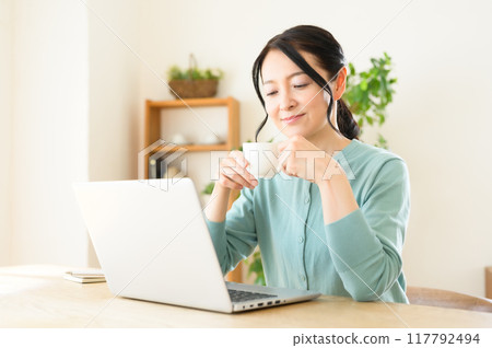 手裡拿著咖啡操作電腦的中年婦女 手裡拿著咖啡操作電腦的中年婦女 117792494