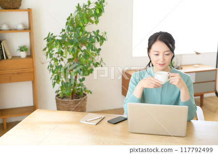 手裡拿著咖啡操作電腦的中年婦女 117792499