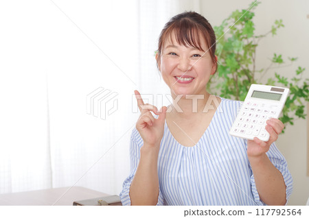 Smiling middle-aged woman holding a calculator 117792564