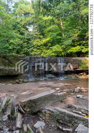 A beautiful view of a waterfall hidden away in a lush and green forest. A beautiful view of a waterfall hidden away in a lush and green forest. 117792738