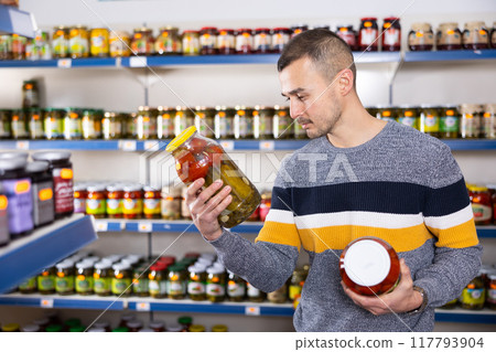In Russian goods store, man choose jar of pickled tomatoes and cucumbers In Russian goods store, man choose jar of pickled tomatoes and cucumbers 117793904