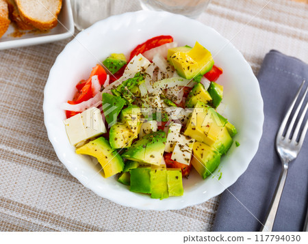 Healthy vegetable salad of sliced fresh tomatoes, avocado and onion 117794030