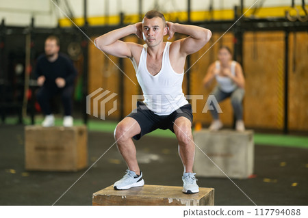 Man jumping up on box at functional cross training in gym 117794088