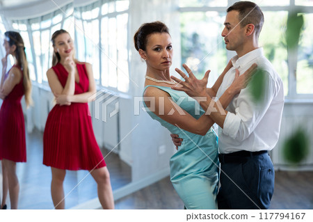 Female tango teacher performing with male student in dance hall 117794167