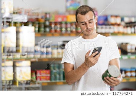 Young man scanning qr code for canned food Young man scanning qr code for canned food 117794271