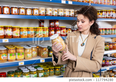 Adult woman chooses sauerkraut in store Adult woman chooses sauerkraut in store 117794280
