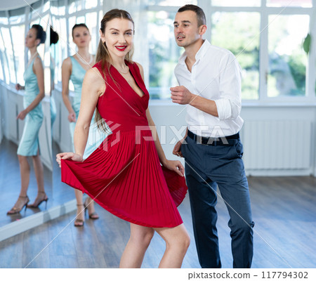Couple in stage costumes learns boogie woogie dancing during individual lesson 117794302
