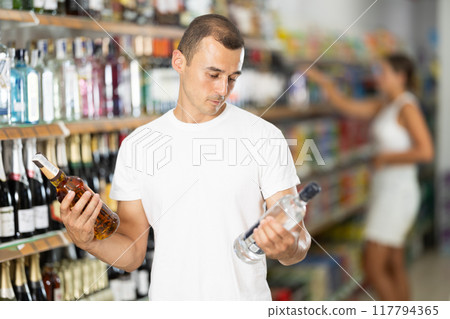 Male shopper selects wodka in produce section of supermarket 117794365