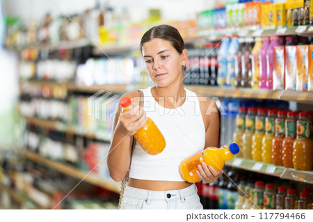 Girl in supermarket buys bottle of soda drink Girl in supermarket buys bottle of soda drink 117794466