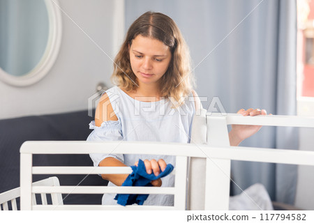 Young woman cleaning chair in living room 117794582