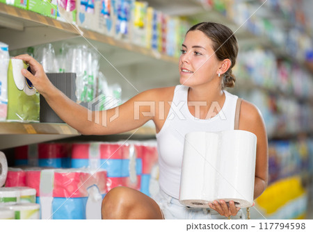 Female customer in store chooses package of toilet paper Female customer in store chooses package of toilet paper 117794598