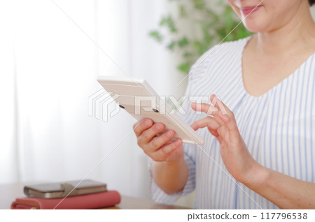 中年婦女用計算機算錢 117796538