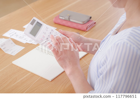A middle-aged woman calculating money with a calculator 117796651