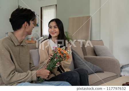 Couple Exchanging Bouquet and Smiles in Living Room Couple Exchanging Bouquet and Smiles in Living Room 117797632