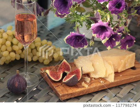 Peeled and cut fresh figs with grapes and cheese, rose wine on terrace sunny day. Food and drink of Mediterranean. Summer and vacation. Peeled and cut fresh figs with grapes and cheese, rose wine on terrace sunny day. Food and drink of Mediterranean. Summer and vacation. 117798274