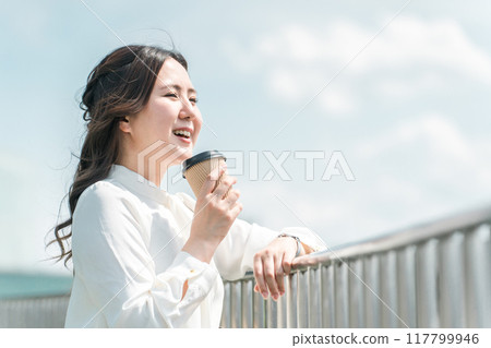 年輕女子一邊喝咖啡一邊看風景（見面、提神、放鬆、約會、散步） 117799946