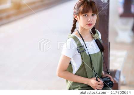 Portrait Young asian woman smiling tourist Traveler girl walking and with a holding the camera waits train travel journey is taken in railway platform Thailand, summer relax vacation Concept. Portrait Young asian woman smiling tourist Traveler girl walking and with a holding the camera waits train travel journey is taken in railway platform Thailand, summer relax vacation Concept. 117800654