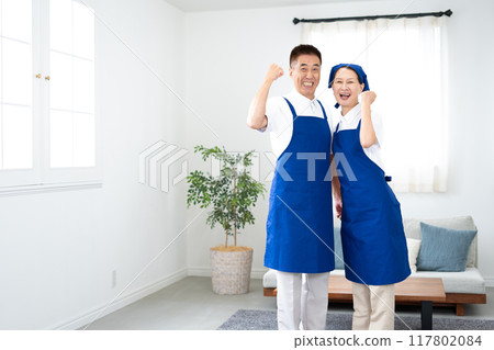 Senior housekeeper in a white polo shirt with a blue apron (male and female, married couple, independent, retired) 117802084