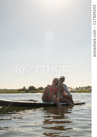 Women Enjoying Paddleboarding on a Sunny Day Women Enjoying Paddleboarding on a Sunny Day 117804205