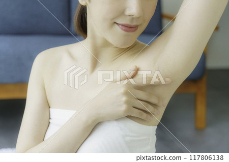 A young woman taking care of her armpits in the living room 117806138