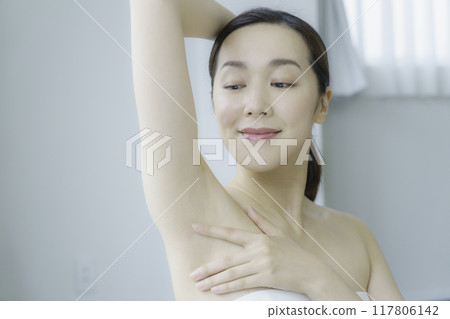 A young woman taking care of her armpits in the living room A young woman taking care of her armpits in the living room 117806142