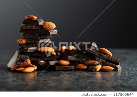 Broken dark chocolate bar with almond on a black background. Broken dark chocolate bar with almond on a black background. 117806644