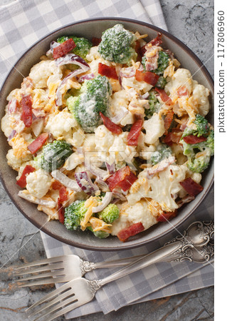 Steamed Broccoli, Cauliflower Salad with Bacon, onion, cheese and mayonnaise dressing closeup on the plate. Vertical top view Steamed Broccoli, Cauliflower Salad with Bacon, onion, cheese and mayonnaise dressing closeup on the plate. Vertical top view 117806960