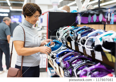 Elderly woman chooses iron in store 117807081