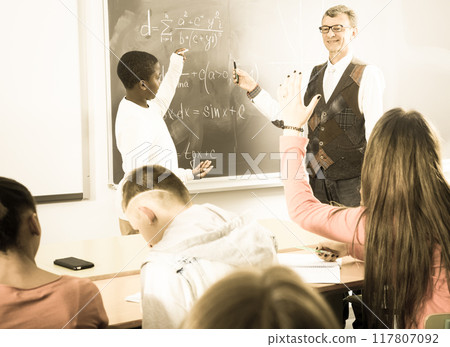 Student from Africa answers on the board during a math lesson 117807092