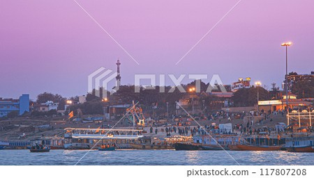 Varanasi, India. Many Boats Moored On Ganga River Near Ghats. General View On Ghats Of Varanasi. Ferris Wheel And Attractions. Purple Sunset Sky At Evening . Evening At Sacred Varanasi Ghats Varanasi, India. Many Boats Moored On Ganga River Near Ghats. General View On Ghats Of Varanasi. Ferris Wheel And Attractions. Purple Sunset Sky At Evening . Evening At Sacred Varanasi Ghats 117807208