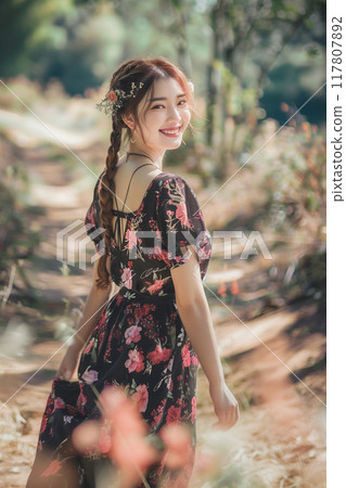 穿著花卉圖案洋裝的亞洲女人站在花田裡 117807892