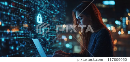 Woman Working on Laptop with Cybersecurity Interface in Background at Night Woman Working on Laptop with Cybersecurity Interface in Background at Night 117809060
