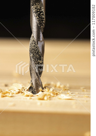 metal drill bit and pine wood board during operation 117809182