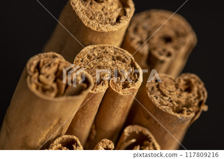 Thick wooden cinnamon on a black slate board Thick wooden cinnamon on a black slate board 117809216