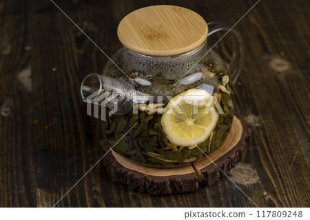 making green tea in a glass teapot with lemon and mint making green tea in a glass teapot with lemon and mint 117809248