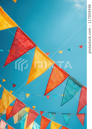 Colorful Festive Bunting Flags Against a Clear Blue Sky on a Sunny Day 117809496