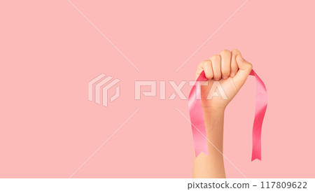 Breast Cancer Awareness Month in October. Women hand holding satin pink ribbon awareness to support and fight for health. Breast cancer screening and prevention campaign banner. 117809622