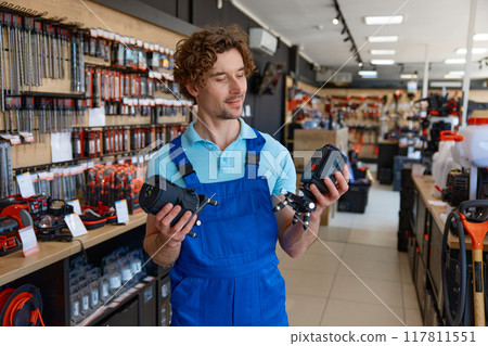 Young salesman in uniform checking laser level at hardware store 117811551