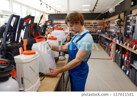 Man worker choosing pressure washer cylinder accessory at hardware store Man worker choosing pressure washer cylinder accessory at hardware store 117811581