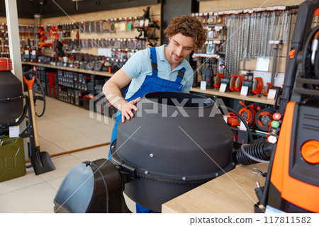 Young man construction worker buying portable concrete mixer at hardware store Young man construction worker buying portable concrete mixer at hardware store 117811582