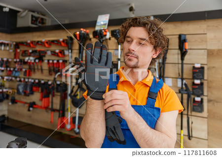 Handsome young hardware store owner putting on construction gloves Handsome young hardware store owner putting on construction gloves 117811608