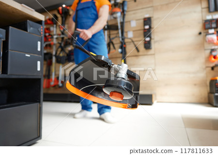 Closeup shot of electric trimmer in hands of hardware shop assistant in overall 117811633